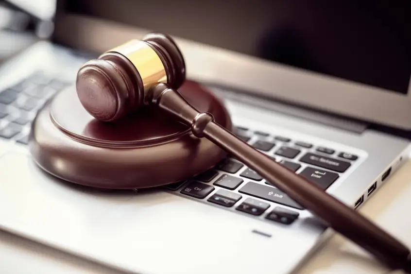 A wooden judge's gavel rests on a laptop keyboard, symbolizing why your court case is online and representing the intersection of law and technology.