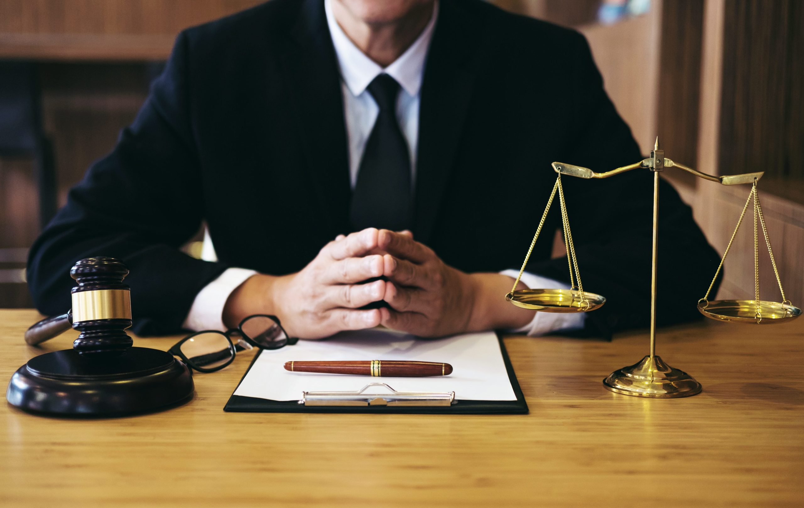 A judge sitting behind a desk with a gavel, scales of justice, and legal documents, conveying a sense of authority and the gravity of judicial proceedings highlights why law firms need online reputation management.