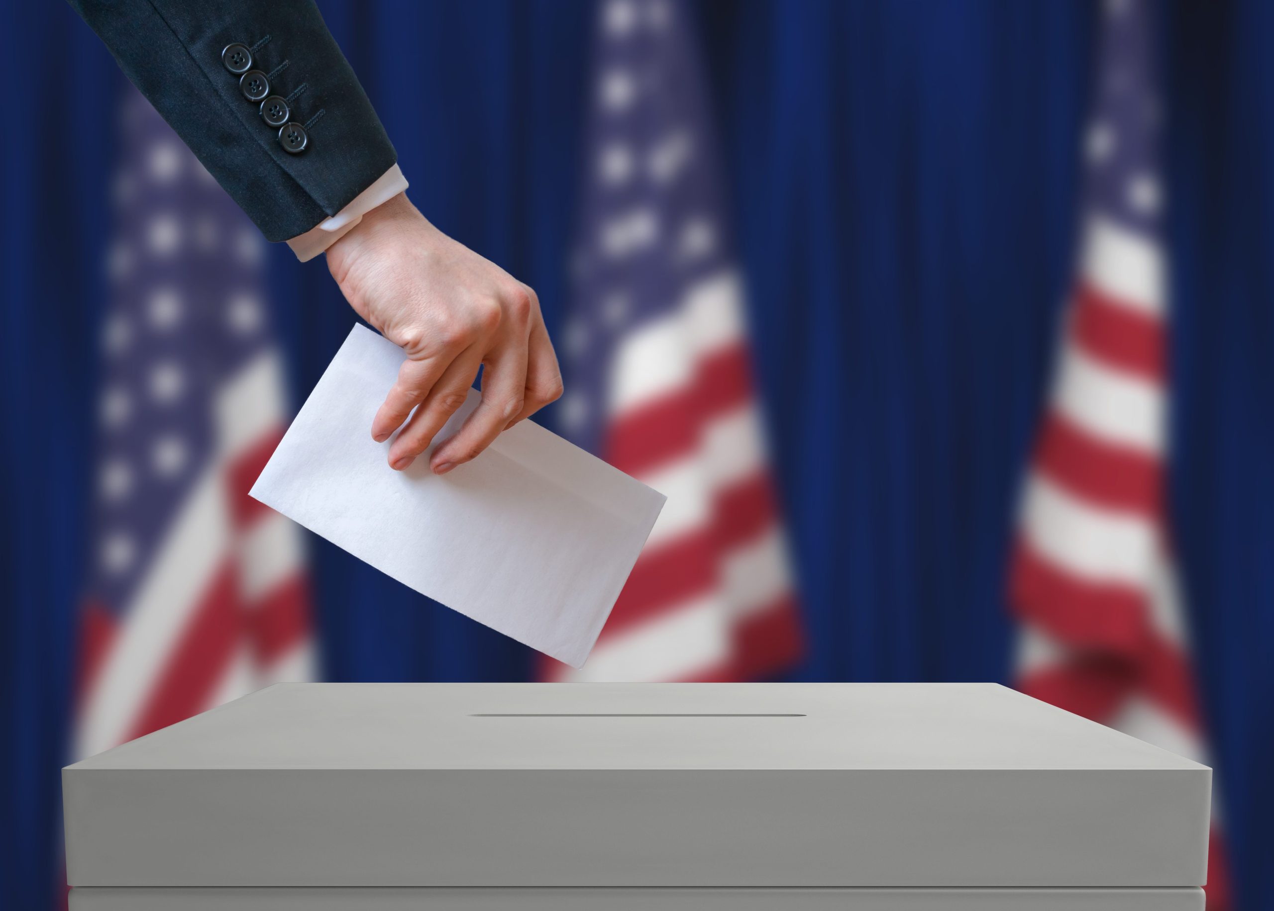 Citizen casting a vote in a ballot box with American flags in the background, symbolizing democracy in action. Fix your social media.