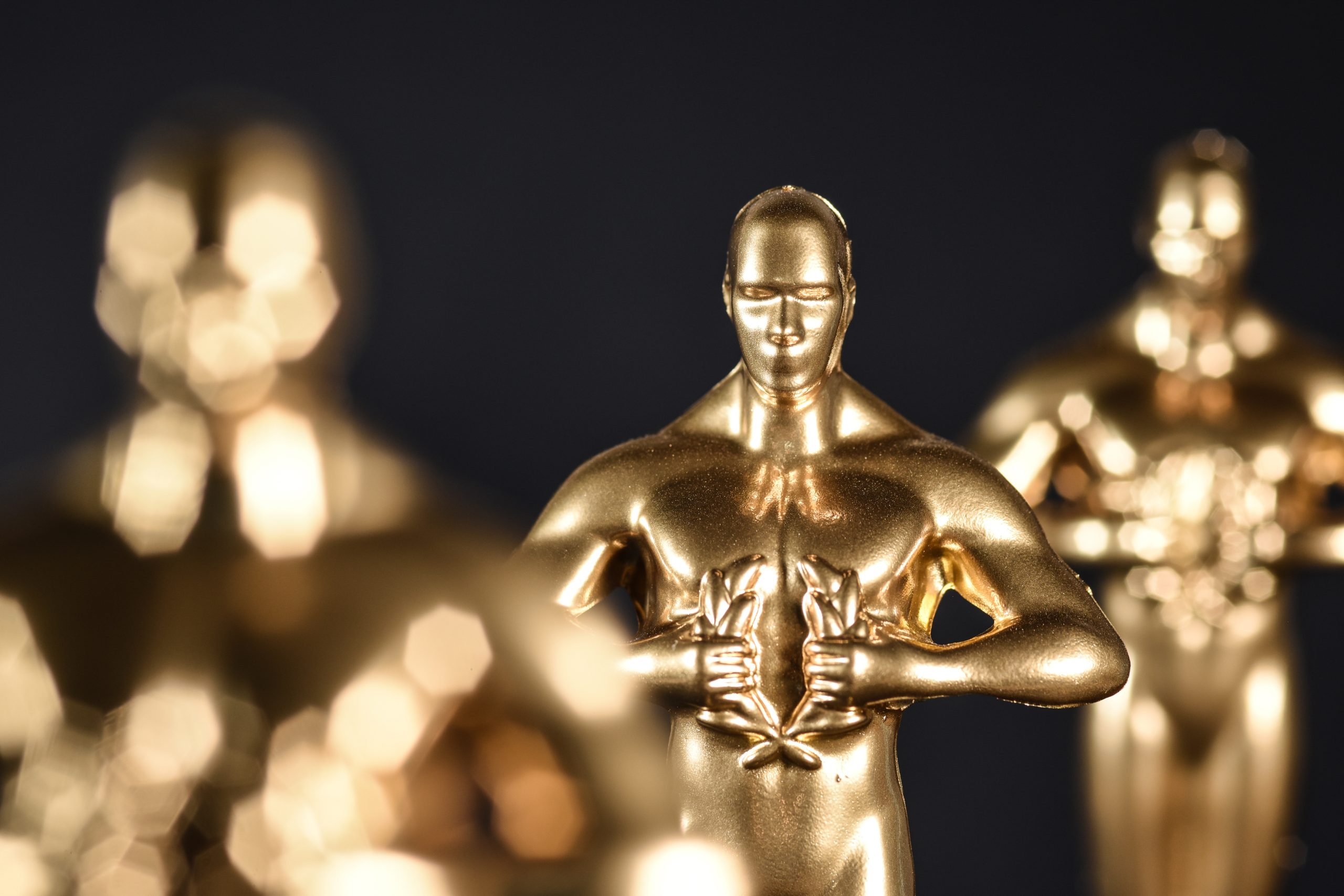 Golden trophy figures standing in the spotlight with a blurred background, evoking the glamour and prestige of an awards ceremony, while subtly hinting at the reputation of the losers.