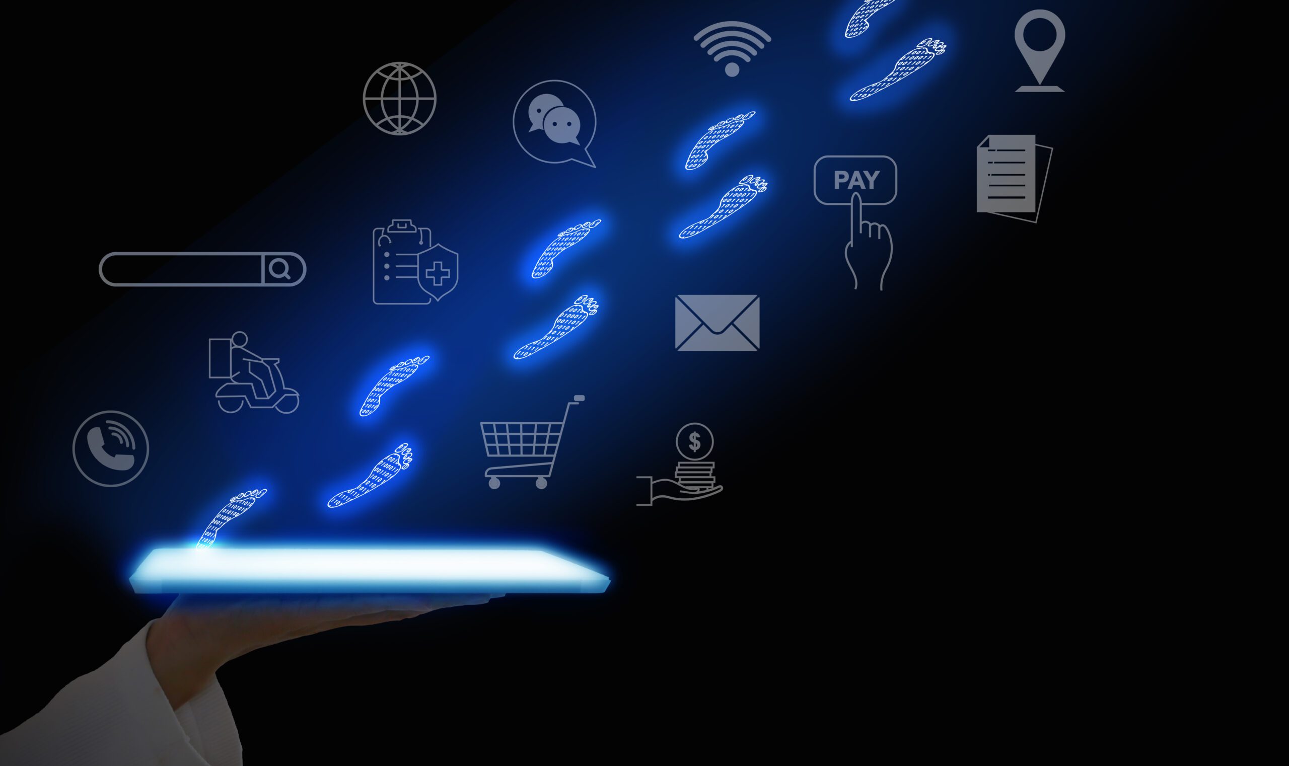 A hand holds a glowing digital tablet emitting blue footprints, leading to various icons such as a globe, chat, Wi-Fi, location, search, cart, email, payment, and document, symbolizing digital connectivity and online services. Black background.